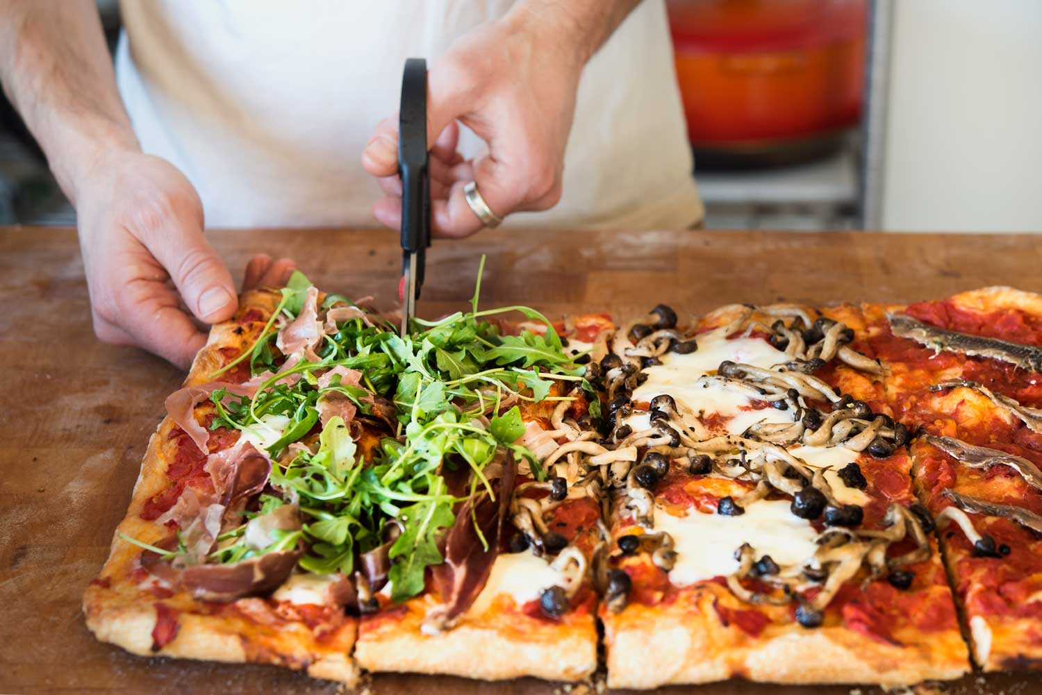A chef dividing a roman style pizza into squares